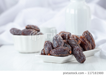 Dates in white dish on a white table. 117181980