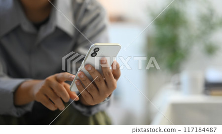 Close up image of woman typing text message or scrolling social media on her mobile phone 117184487