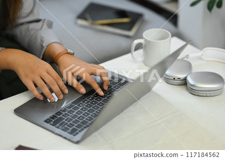 Cropped image of young female freelancer working with laptop in living room Cropped image of young female freelancer working with laptop in living room 117184562