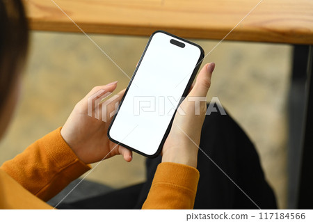 Over the shoulder view of woman holding smartphone with blank screen Over the shoulder view of woman holding smartphone with blank screen 117184566
