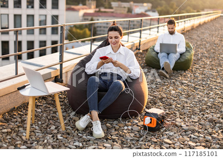 Businesspeople working outdoors on roof with portable power station Businesspeople working outdoors on roof with portable power station 117185101