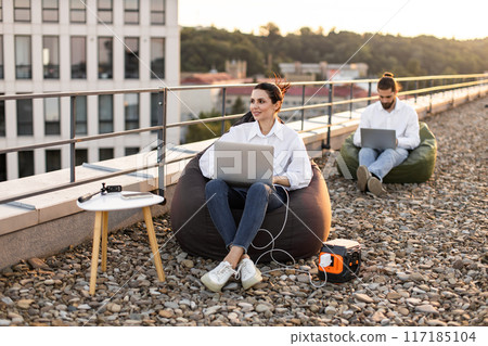 Business people working on rooftop with portable power station 117185104