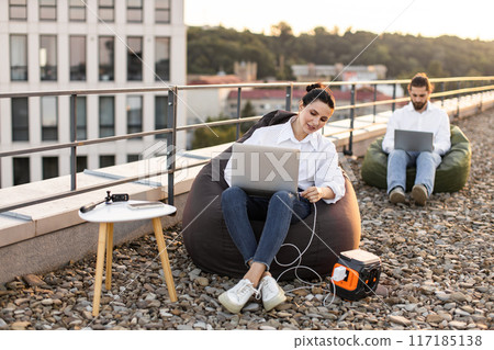 Business professionals working outdoors on rooftop with laptops 117185138