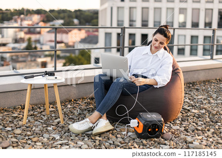 Business woman working on rooftop with portable power station 117185145