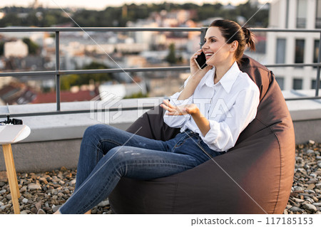 Woman talking on phone outdoors in casual setting 117185153