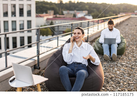 Outdoor workspace with people working on laptops and mobile phone 117185175