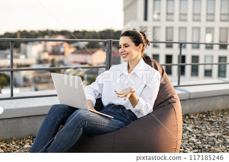 Woman working on laptop outdoors on rooftop terrace 117185246