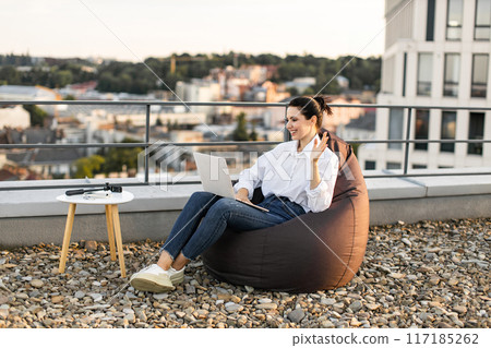 Woman working outdoors with laptop on rooftop terrace 117185262