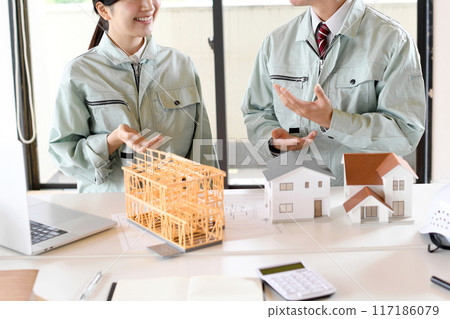 Men and women in work clothes holding a meeting using a construction model 117186079