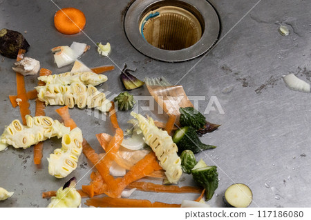 Vegetable scraps and leftovers being dumped into a stainless steel sink 117186080