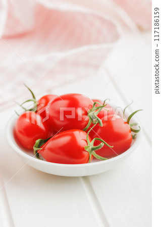 Red cherry tomatoes in bowl on white table. Red cherry tomatoes in bowl on white table. 117186159