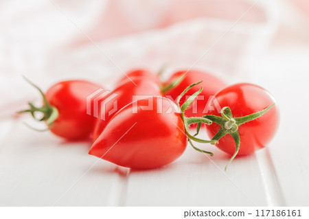 Red cherry tomatoes on white table. 117186161