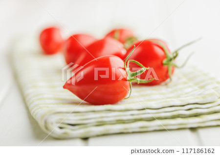 Red cherry tomatoes on checkered napkin. 117186162