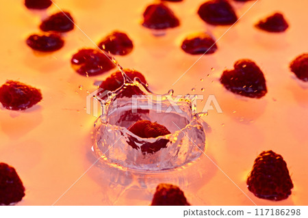 dynamic splash of raspberry hitting water, with scattered berries in background, all bathed in golden glow. dynamic splash of raspberry hitting water, with scattered berries in background, all bathed in golden glow. 117186298