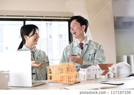 Men and women in work clothes holding a meeting using a construction model Men and women in work clothes holding a meeting using a construction model 117187100