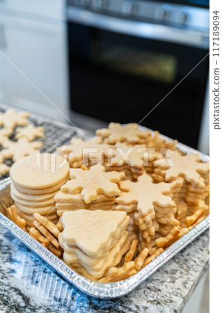Carefully stacking the beautifully crafted snowflake-shaped sugar cookies into a foil pan, ready for freezing as delightful Christmas treats. Carefully stacking the beautifully crafted snowflake-shaped sugar cookies into a foil pan, ready for freezing as delightful Christmas treats. 117189094