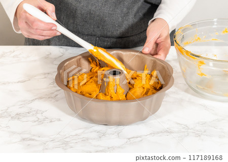 Pouring cake batter into a bundt cake pan, ready to bake a delicious homemade pumpkin bundt cake. 117189168