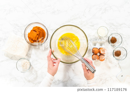 Flat lay. In a cozy kitchen, a large mixing bowl becomes the stage for expertly blending the ingredients, setting the scene for crafting a delightful homemade pumpkin bundt cake from cake mix. Flat lay. In a cozy kitchen, a large mixing bowl becomes the stage for expertly blending the ingredients, setting the scene for crafting a delightful homemade pumpkin bundt cake from cake mix. 117189176