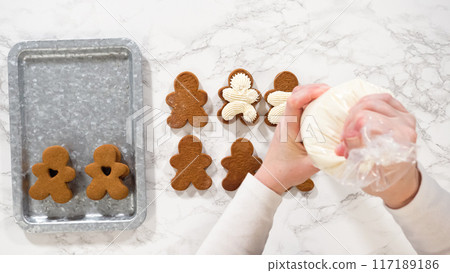 Flat lay. Gingerbread cookies await their second halves on a marble surface, each meticulously piped with buttercream to craft delightful sandwich treats. The precision of the piping adds a festive 117189186