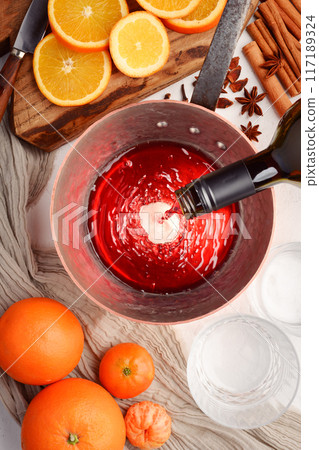 Red wine pouring into a copper pot from bottle 117189324