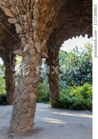 Stone colonnade resembling tree trunks by Antonio Gaudi in Park Guell, Barcelona. The arcade of stone columns Stone colonnade resembling tree trunks by Antonio Gaudi in Park Guell, Barcelona. The arcade of stone columns 117189903