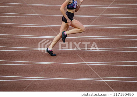 woman athlete running stadium race in background of intersecting marking lines track woman athlete running stadium race in background of intersecting marking lines track 117190490