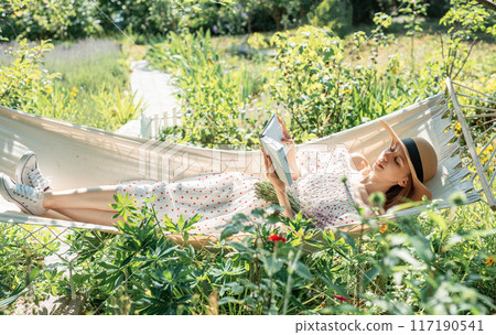 Young woman relaxing in a hammock outdoors in back yard Young woman relaxing in a hammock outdoors in back yard 117190541