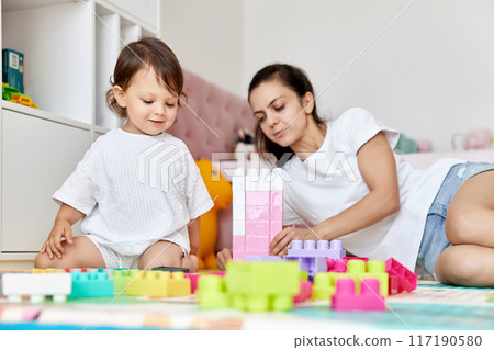 cute baby girl and her loving mother build tower from colorful cubes, early development 117190580