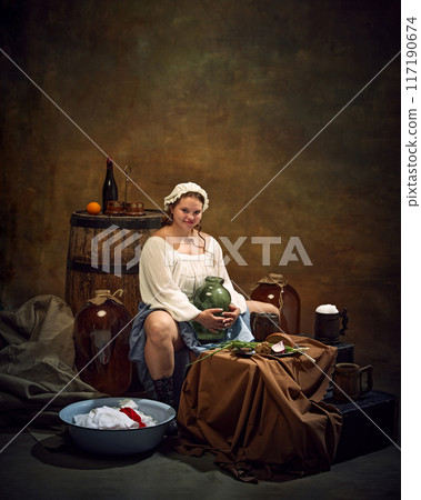 Woman in traditional attire sits with jug, surrounded by rustic items. barrels, basin of clothes, and simple food. Homely atmosphere. Woman in traditional attire sits with jug, surrounded by rustic items. barrels, basin of clothes, and simple food. Homely atmosphere. 117190674