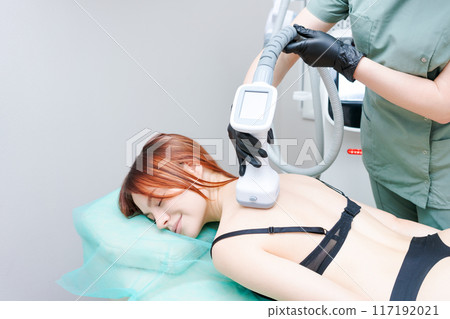 A woman is getting a massage with a device attached to her back 117192021