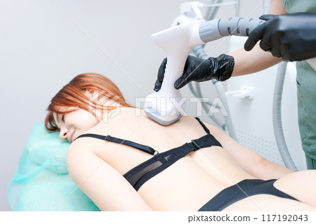 A woman is getting a massage with a machine on her back 117192043