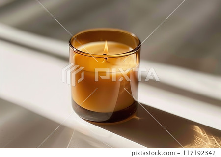 A warm amber candle in a glass holder creates a soft glow, perfect for a calming atmosphere A warm amber candle in a glass holder creates a soft glow, perfect for a calming atmosphere 117192342