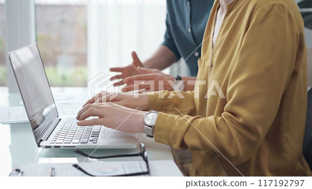 Team collaboration over financial reports. Business people, professionals analyzing financial charts and data on a desk while sitting near a laptop computer 117192797