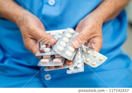 Senior Asian woman holding capsule pills drug in blister packaging for treatment infection patient in hospital. Senior Asian woman holding capsule pills drug in blister packaging for treatment infection patient in hospital. 117192837