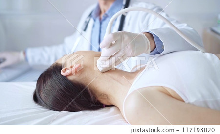 Doctor man is using ultrasound equipment on neck of female patient lying down for a medical examination. Medicine and science 117193020