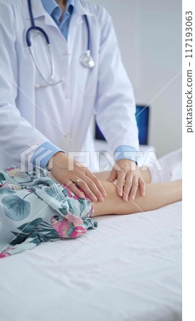 Doctor and kid patient. Orthopedist examining girl's knee in medical clinic. Medicine and health care 117193063