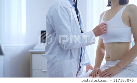 Doctor and patient. Physician is using stethoscope examining woman lungs in clinic cabinet. Medicine and health care Doctor and patient. Physician is using stethoscope examining woman lungs in clinic cabinet. Medicine and health care 117193076