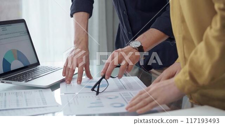 Business people, professionals analyzing financial charts and data on a desk while standing and using laptop computer in office. Dark blue shirt and yellow blouse 117193493
