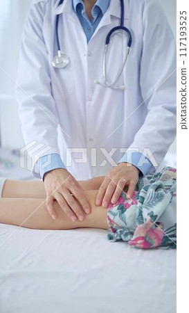 Doctor and kid patient. Orthopedist examining girl's knee in medical clinic. Medicine and health care 117193525