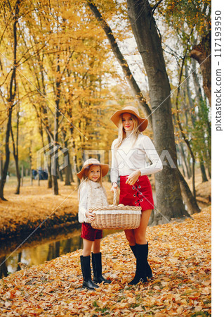 Fashionable mother with daughter. Family in a autumn park. 117193950