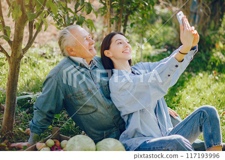 Senior with box of apple. Brunette in a blue shirt. Grandfather with grandaughter. Senior with box of apple. Brunette in a blue shirt. Grandfather with grandaughter. 117193996