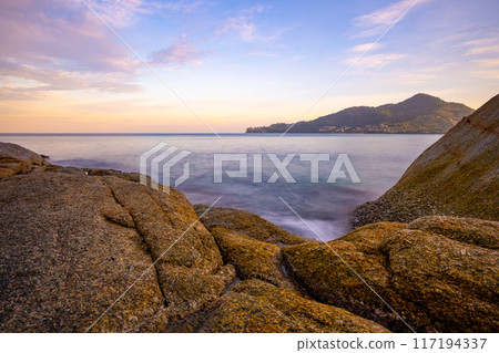 Long exposure image of Dramatic sky seascape with rocks and waves crashing on seashore in sunset or sunrise scenery background Long exposure image of Dramatic sky seascape with rocks and waves crashing on seashore in sunset or sunrise scenery background 117194337