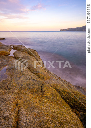 Long exposure image of Dramatic sky seascape with rocks and waves crashing on seashore in sunset or sunrise scenery background 117194338