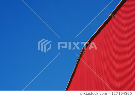 Abstract architecture. Detail of red building facade with metal siding on blue sky, nobody. Low angle view 117194590