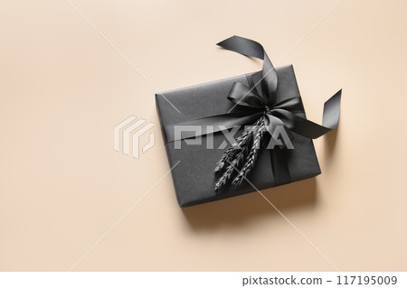 Festive back gift wrapped in paper with ribbon on biege background. Copy space. Present for Father Day. Black Friday. 117195009