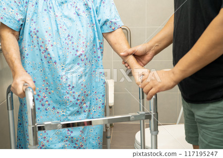Caregiver help Asian elderly woman patient use walker and toilet bathroom handle security. Caregiver help Asian elderly woman patient use walker and toilet bathroom handle security. 117195247