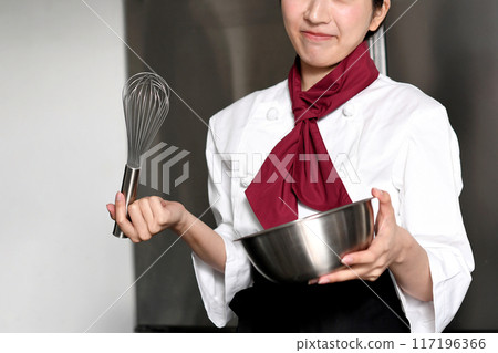 年輕的亞洲女廚師在廚房擔心 年輕的亞洲女廚師在廚房擔心 117196366