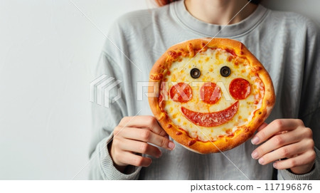 Holding Pizza with Smiley Face Toppings. A person holding a pizza with toppings arranged to form a smiley face, creating a fun and cheerful vibe. 117196876