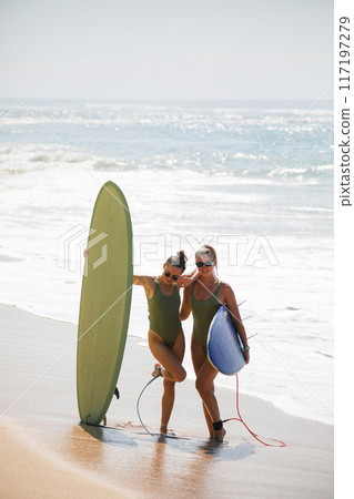 Two beautiful blondes in swimsuits pose with surfboards on the beach 117197279