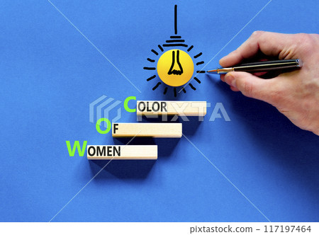 WOC women of color symbol. Concept words WOC women of color on beautiful wooden blocks. Beautiful blue background. Businessman hand. Business WOC women of color social issues concept. Copy space. 117197464